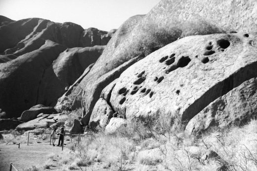Black and white photograph of Uluru with two people standing to the side