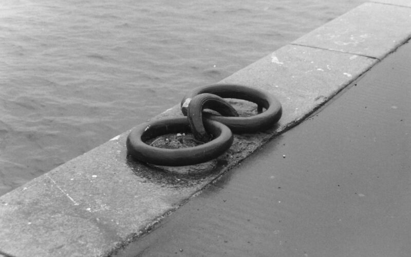 Black and white photograph of large mooring rings set into the stonework of a pier
