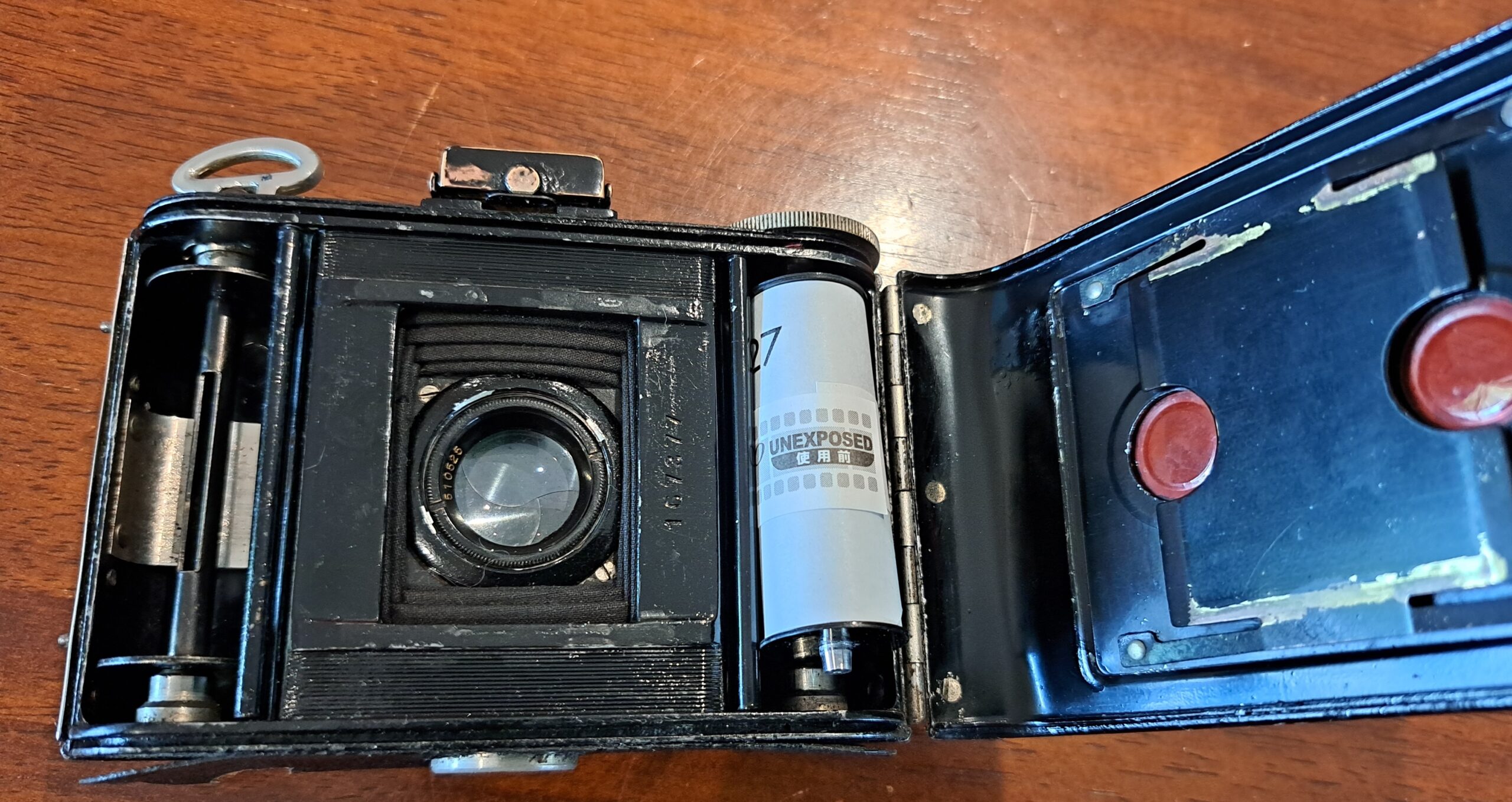 Vintage camera with the back open and a roll of 127 film in the right hand side ready to load.