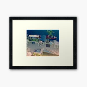 Photo framed in a black frame with a large white border. The photo is looking down on a river with a red boat alongside a jetty, which is next to a pool where there are people in a spa. It is signed by Frogmouth Cottage Photograpy.