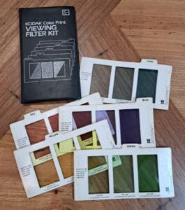 Photograph of a folder labelled "KODAK Color Print FILTER VIEWING KIT" with five filter cards - Cyan, Red, Blue, Yellow and Green. Each card has three sections with filters inserted and increasing densities.