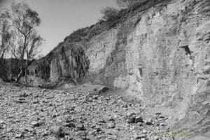 Black and white photo of a wall of ochre in different shades, carved out by indigenous peoples