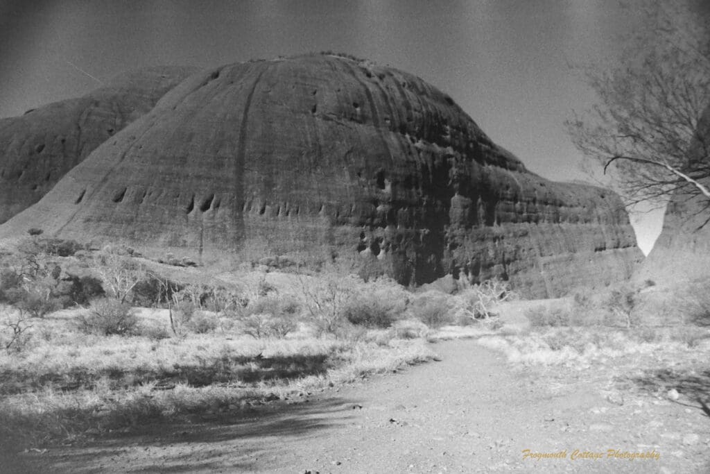 Black and white photograph of two very large rock formations and a path leading towards the gap in between